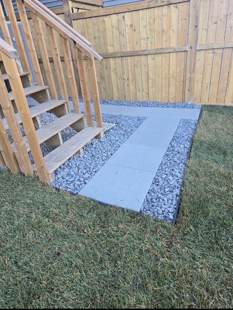 Paver walkway with rock border leading to deck stairs